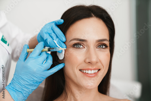 Photo of smiling woman getting mesotherapy treatment in face photo