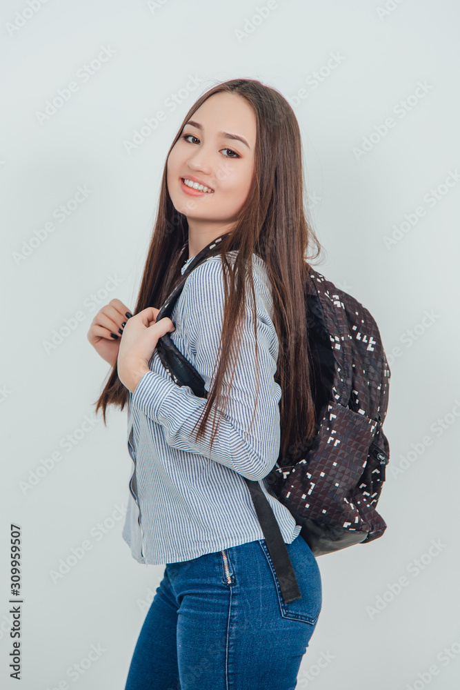 Cute young asian girl in casual clothes standing with backpack behind shoulders, smiling lovely, looking at the camera. Cute young asian girl in casual clothes standing with backpack behind shoulders, smiling lovely, looking at the camera.