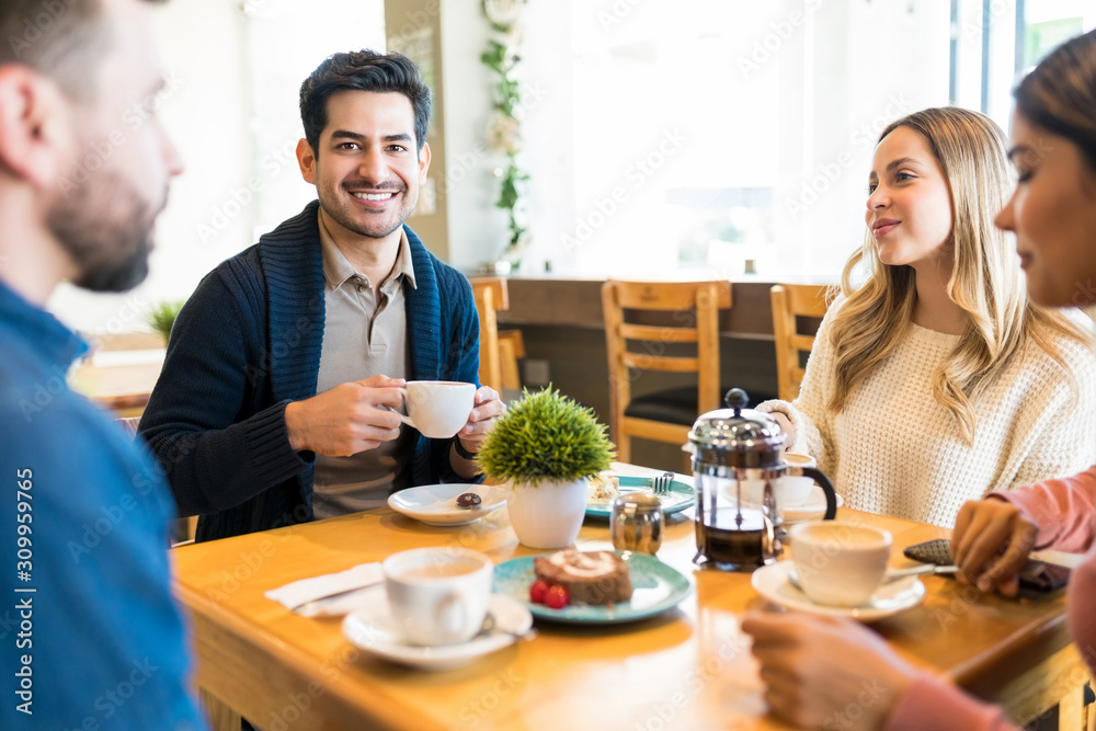 Hispanic Male Having Coffee With Friends At Cafe Hispanic Male Having Coffee With Friends At Cafe