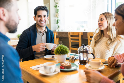 Hispanic Male Having Coffee With Friends At Cafe