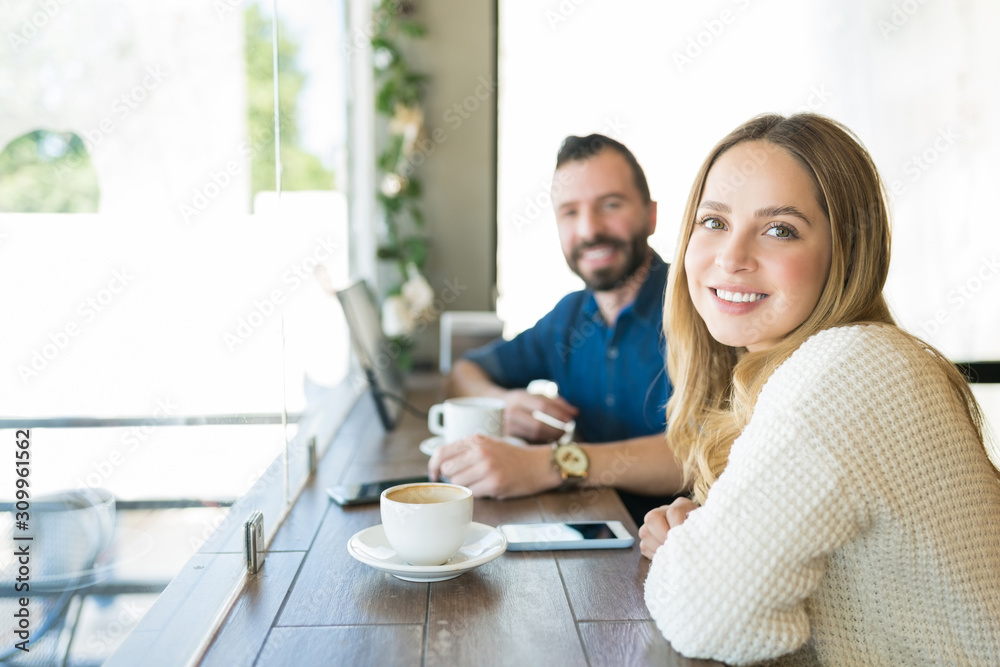 Smiling Female Sitting With Male Friend By Window At Cafe Smiling Female Sitting With Male Friend By Window At Cafe