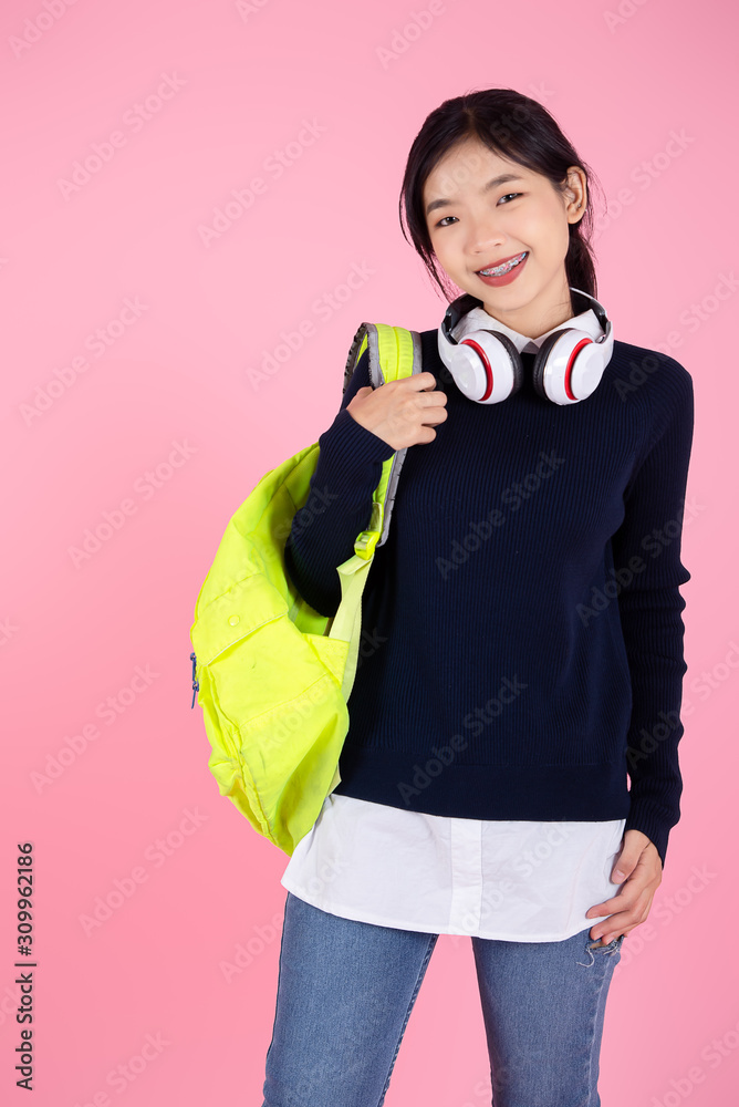 Obraz premium Asian student with backpack and headphone on pink background.