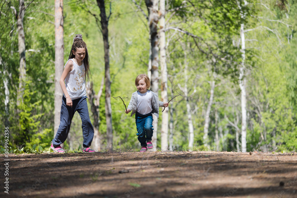 Children walk and have fun in the forest on summer day.