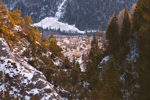 Blick von einem Gebirgstal hinunter in das winterliche Mittenwald mit Häusern in der Morgensonne photo