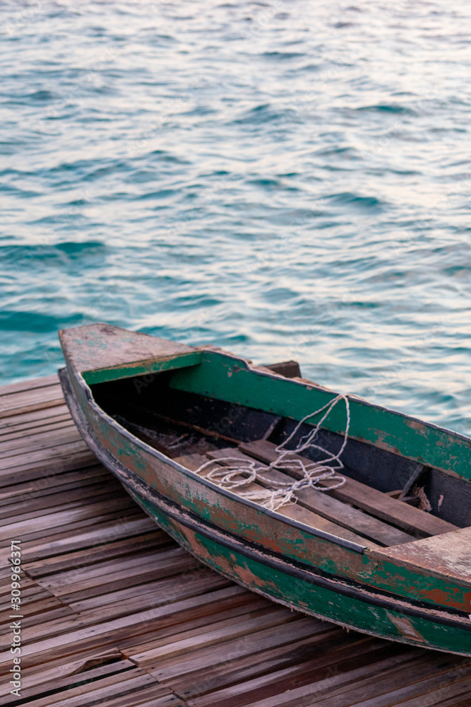 Old wooden boat sitting on the pier overlooking the beautiful Semporna turquoise sea.