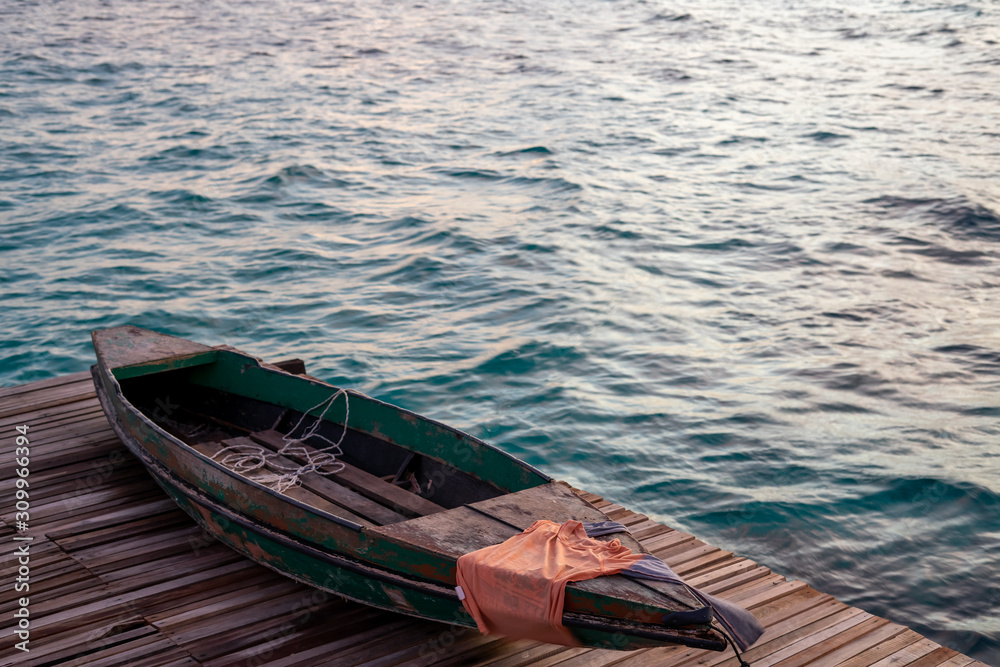 Old wooden boat sitting on the pier overlooking the beautiful Semporna turquoise sea.