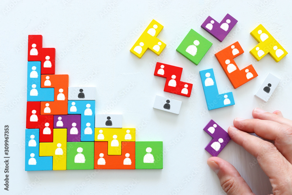 Business concept image of tangram puzzle blocks with people icons over wooden table, human resources and management concept Business concept image of tangram puzzle blocks with people icons over wooden table, human resources and management concept