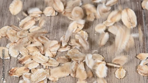 Close up oatmeal flakes falling on wooden table photo