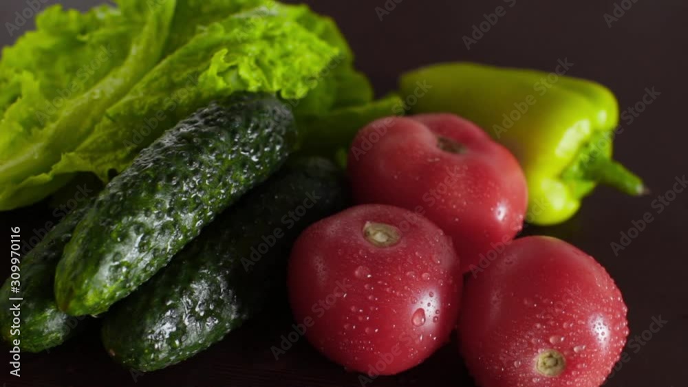 wet tomatoes, lettuce and cucumbers on dark wooden kitchen table wet tomatoes, lettuce and cucumbers on dark wooden kitchen table