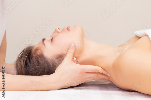 massage and stretching of the cervical muscles. Beautiful girl gets massage in a spa salon. light tones photos. concept of massage and health. rheumatism, arthrosis