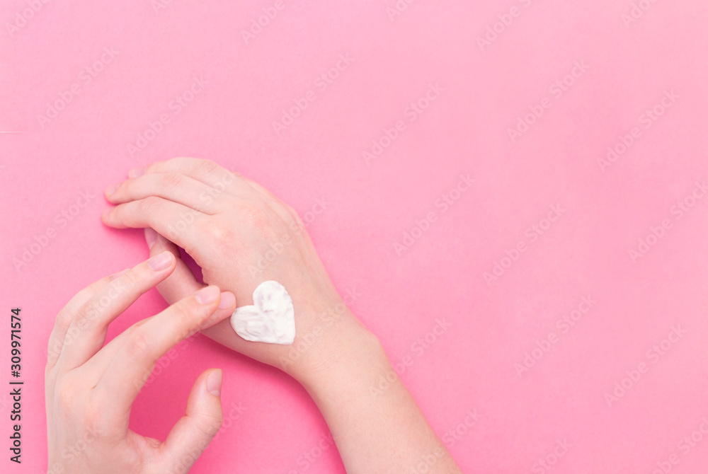 Hands of a beautiful well-groomed woman with a cream jar on a pink textural background. Moisturizer for clean and soft skin in the winter. The heart shape is made of cream. I love the body. Hands of a beautiful well-groomed woman with a cream jar on a pink textural background. Moisturizer for clean and soft skin in the winter. The heart shape is made of cream. I love the body.