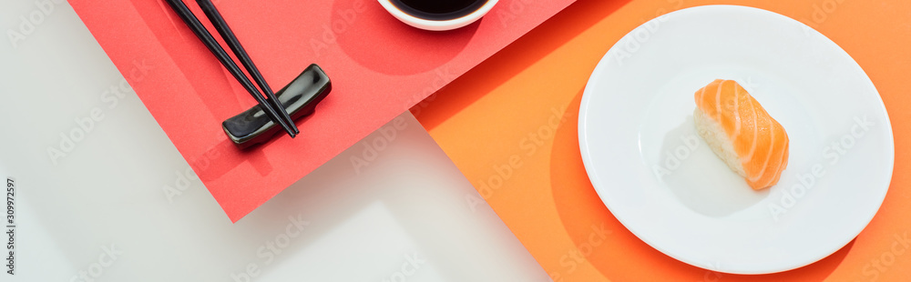 fresh nigiri with salmon near soy sauce and chopsticks on red, orange, white surface, panoramic shot fresh nigiri with salmon near soy sauce and chopsticks on red, orange, white surface, panoramic shot