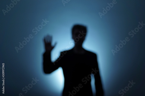 Unfocused backlit man moves his hand to say hello. Near-death experience. Dream image. © Gaetan