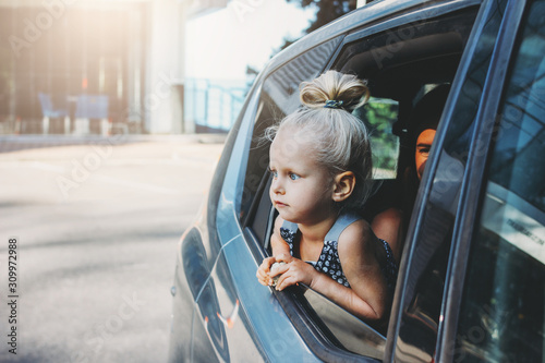 Little baby toddler girl looks out of car window with her mom
