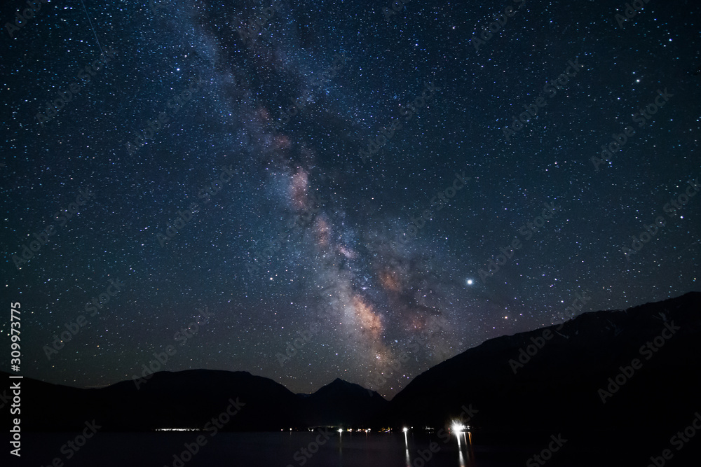 Arm of Milky Way galaxy visible over mountain lake