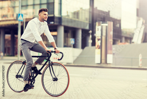lifestyle, transport and people concept - young man with headphones riding bicycle on city street