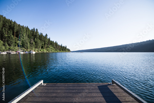 Fototapeta Naklejka Na Ścianę i Meble -  Wooden dock extends over placid mountain lake