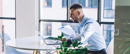 Photography Interested businessman reviewing report and surfing laptop at work
