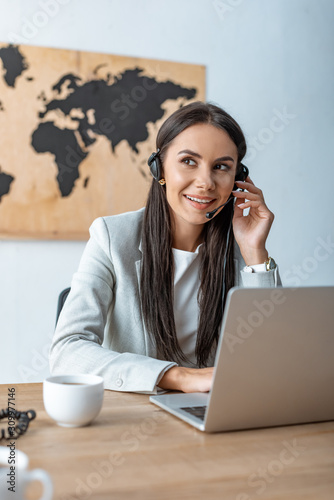 smiling travel agent working near laptop photo