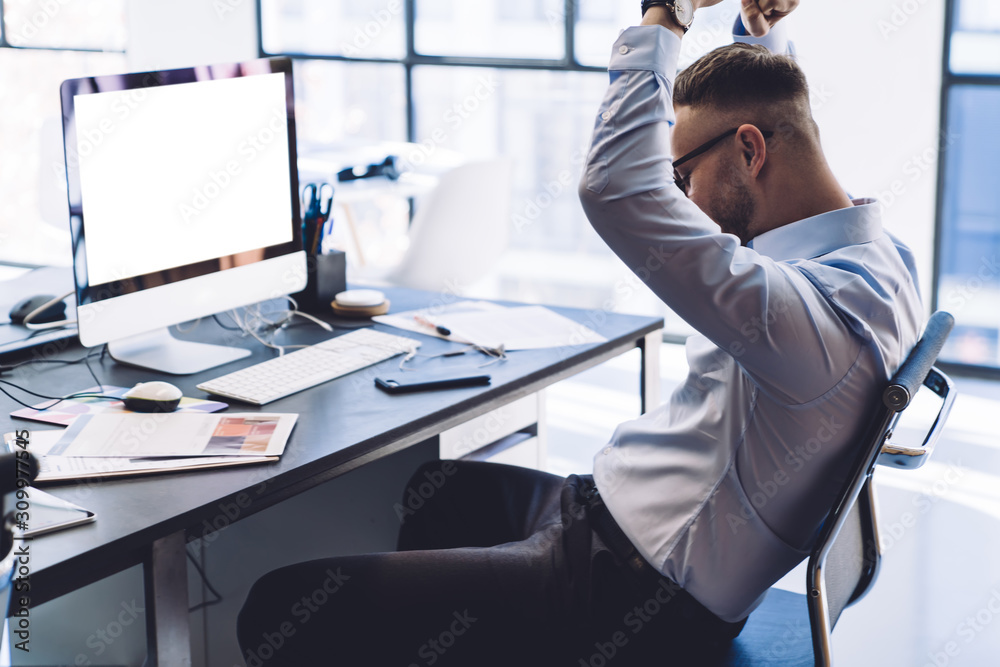 Cheerful man raising hands celebrating victory in working process Cheerful man raising hands celebrating victory in working process
