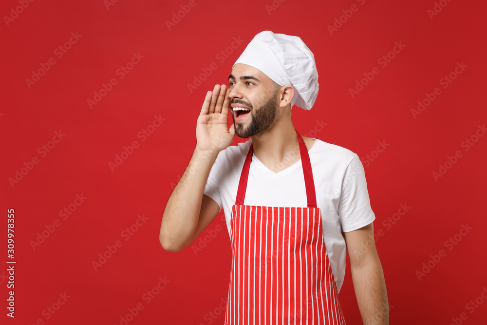Young bearded male chef cook or baker man in striped apron toque chefs hat posing isolated on red background. Cooking food concept. Mock up copy space. Looking aside, screaming with hand near mouth. Young bearded male chef cook or baker man in striped apron toque chefs hat posing isolated on red background. Cooking food concept. Mock up copy space. Looking aside, screaming with hand near mouth.