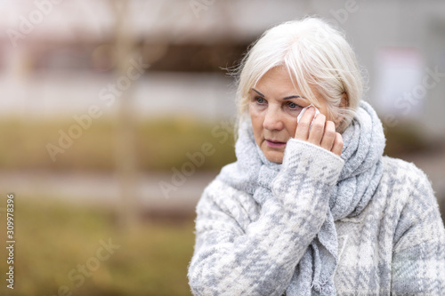 Weeping old woman wipes her eyes with tissue