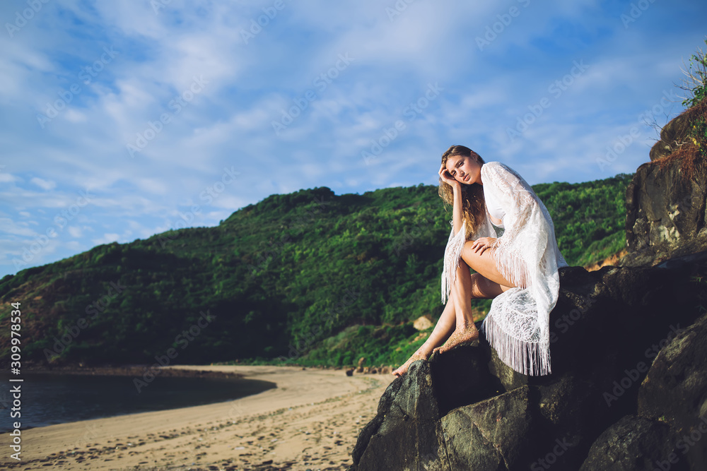 Young woman resting on stone near sea