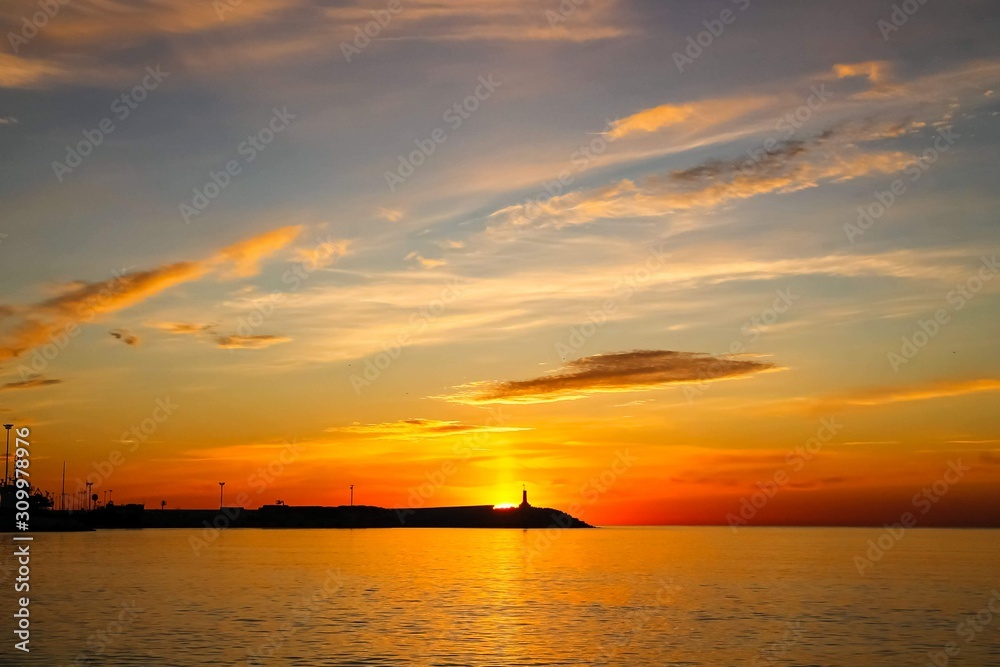 Sunrise in Malaga, Spain. Lighthouse on the horizon