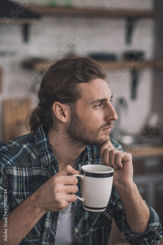 Thoughtful romantic man having a cup of coffee