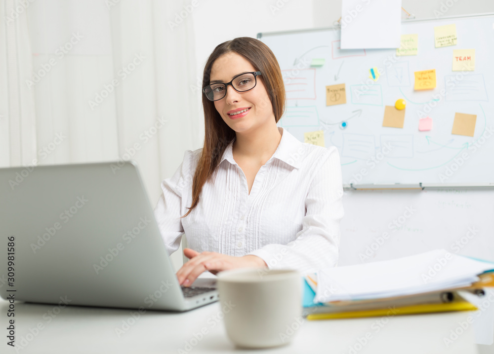 Portrait of a smiling young business woman manager at workplace. Portrait of a smiling young business woman manager at workplace.