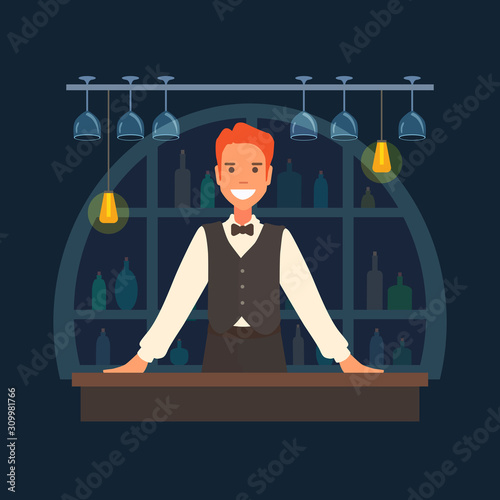 An elegant bartender leans his hands on the bar. Shelves with bottles. Wine glasses hanging from above. Man in a suit waistcoat and bowtie smiling. 