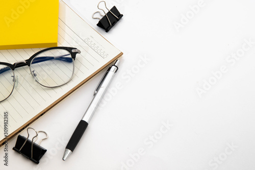 pen and glasses on a notebook in white background 