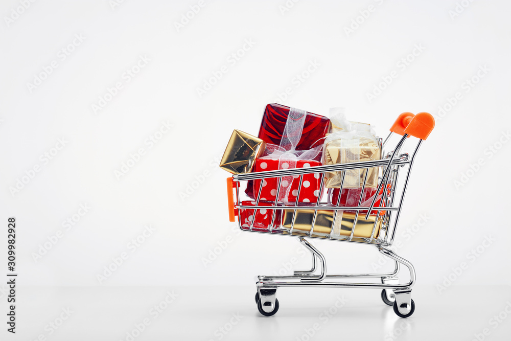 Shopping cart trolley full of colorful gift boxes on white background