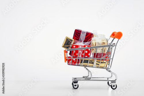 Shopping cart trolley full of colorful gift boxes on white background
