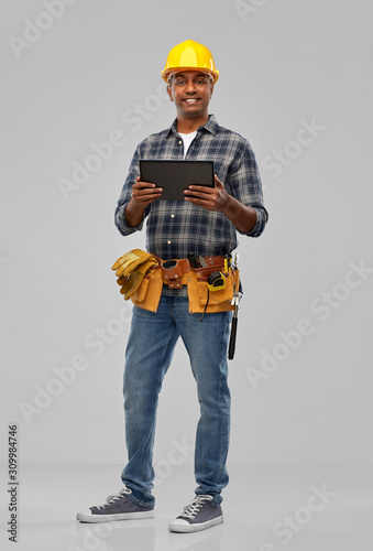 profession, construction and building - happy smiling indian worker or builder in helmet with tablet pc computer over grey background