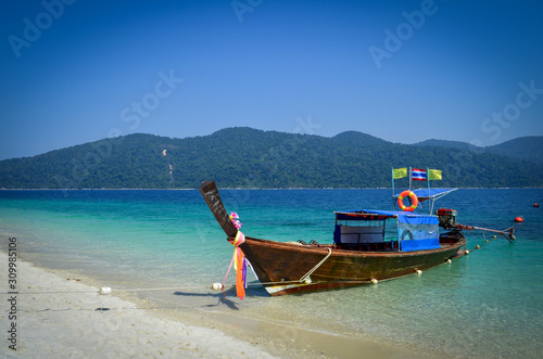 Clear blue sky over mountain and sea that have beautiful clear water and Thai traditional boat anchor on the beach at Satun province, Thailand that have white find sand and beautiful ocean view.