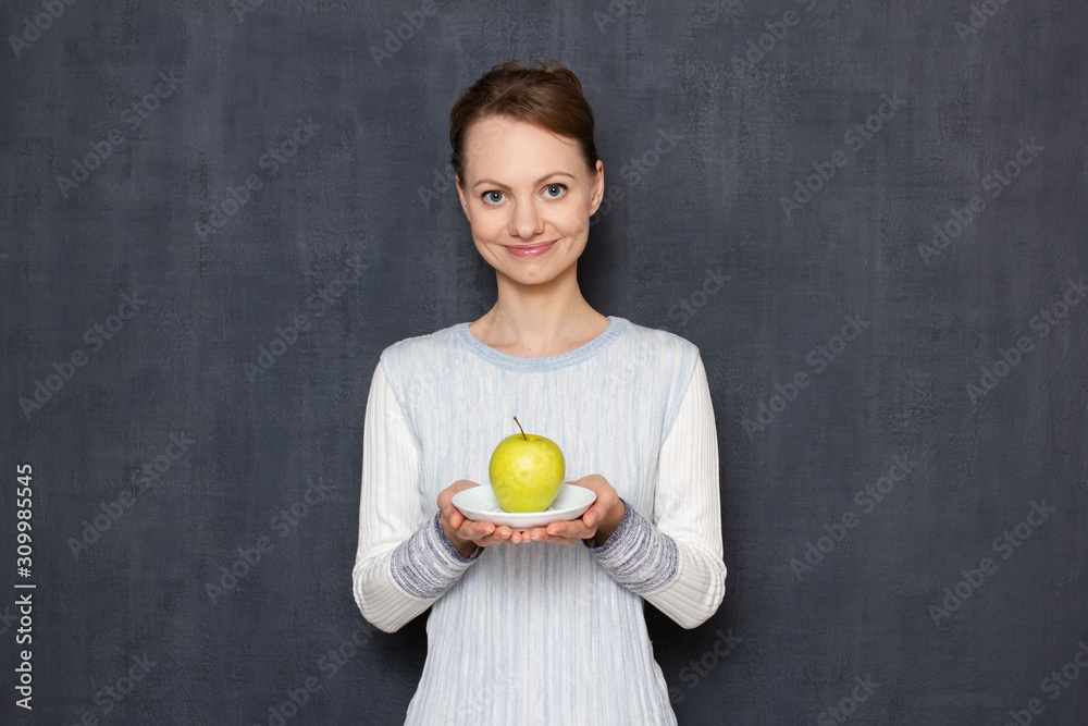 Portrait of happy young woman smiling and holding plate with apple Portrait of happy young woman smiling and holding plate with apple