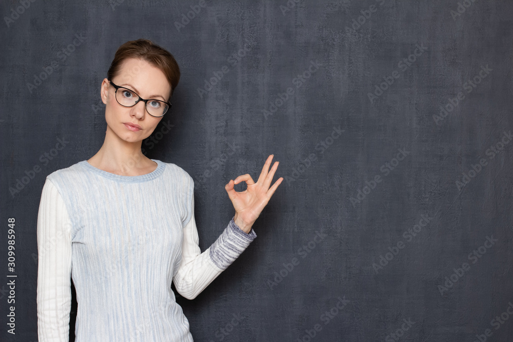 Portrait of serious woman with glasses, showing okay gesture or zero Portrait of serious woman with glasses, showing okay gesture or zero