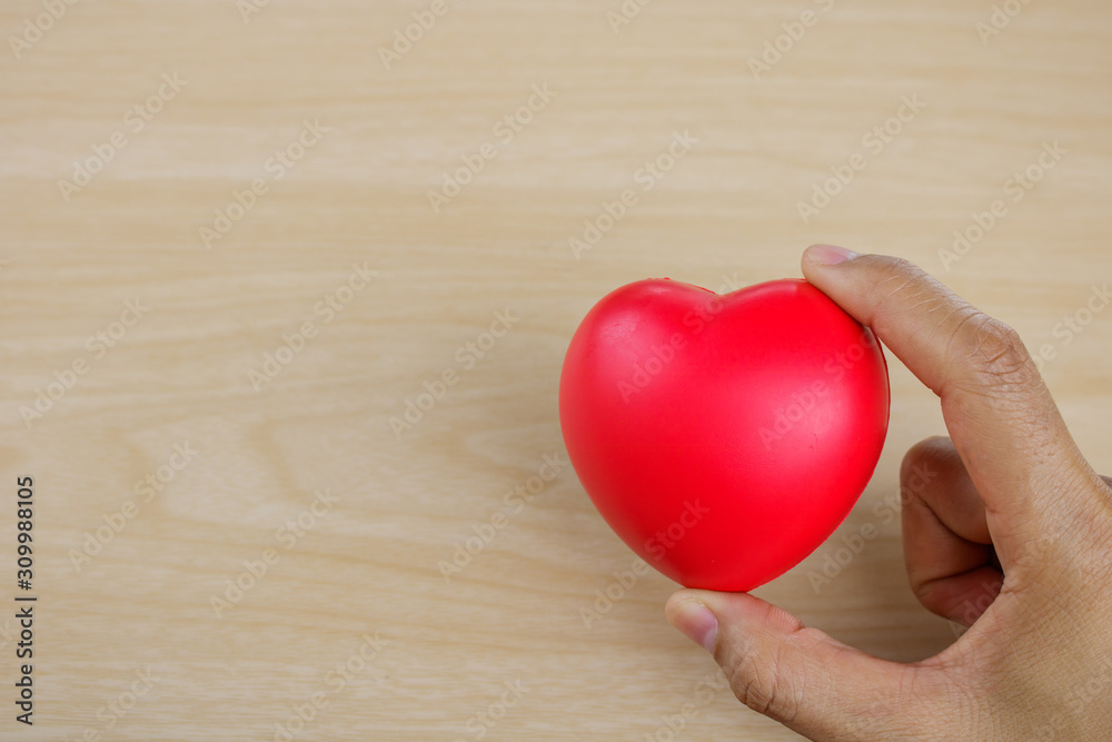 Red heart on hand on wooden background. Red heart on hand on wooden background.