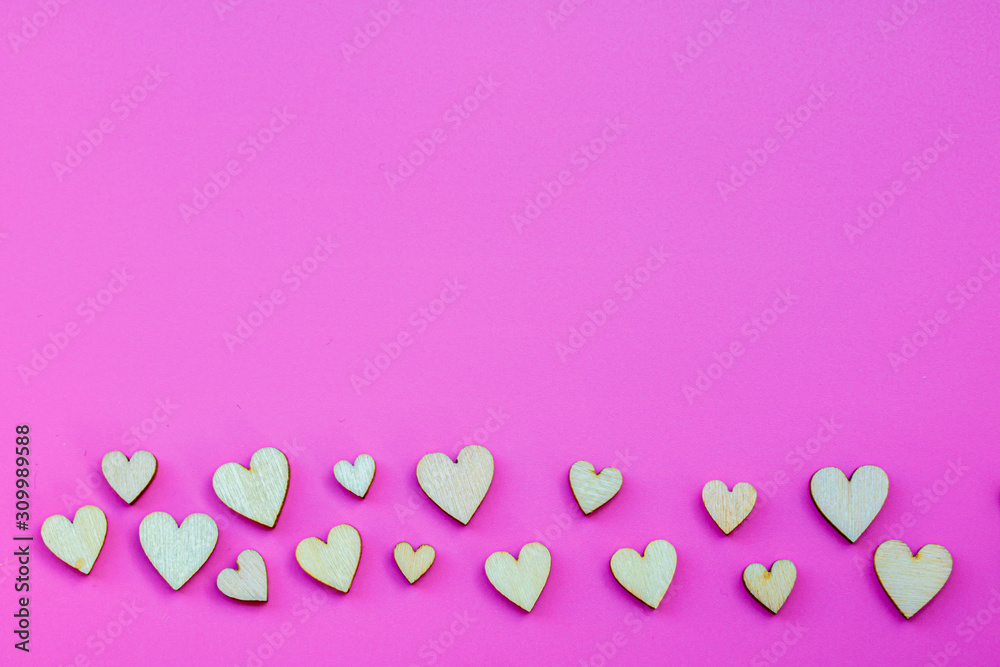 Many small wooden hearts on a pink background and copy space. Many small wooden hearts on a pink background and copy space.