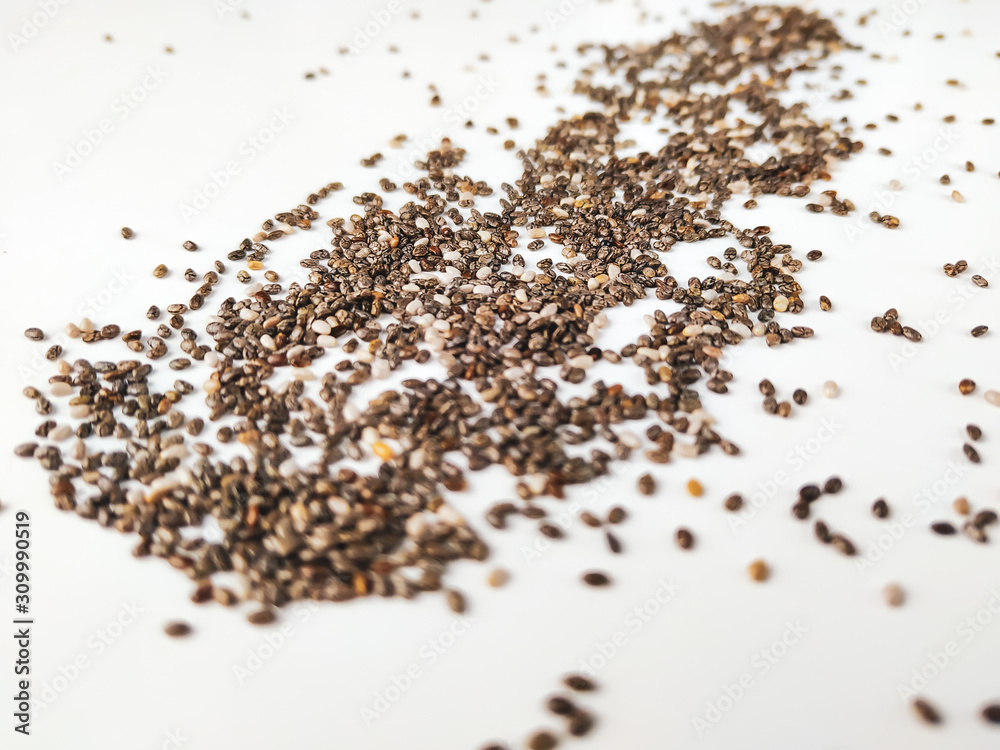 Closeup of chia seed superfood raw and organic on white background, with seeds randomly placed in space