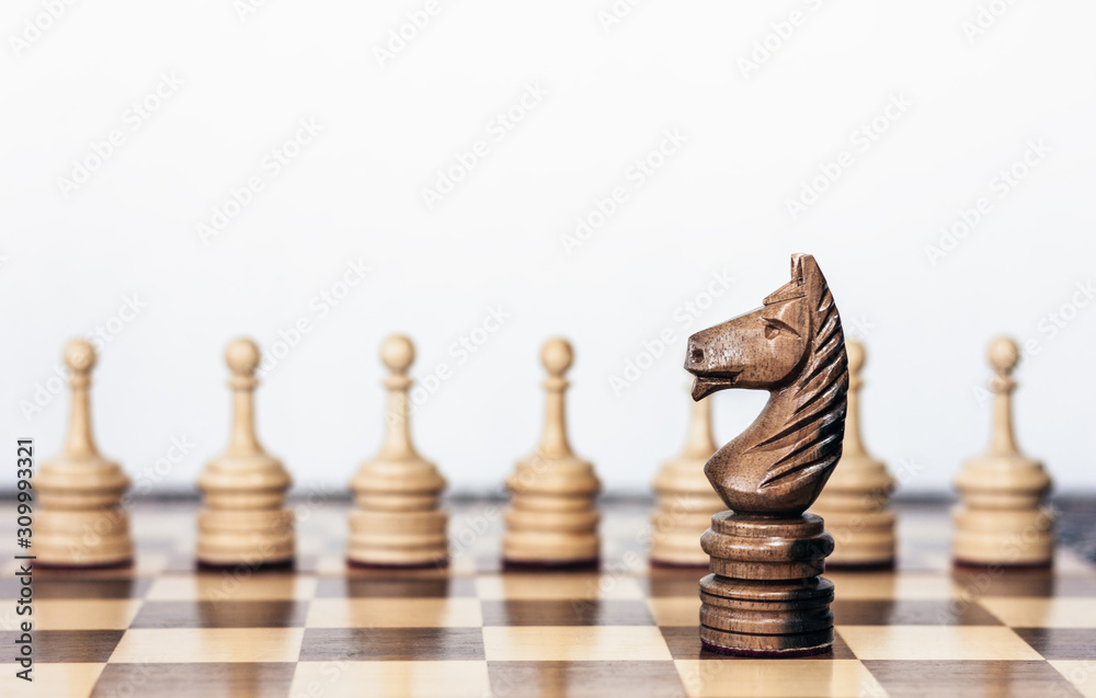 Wooden black and white chess pieces on a chessboard, horse and pawns on the background, leadership retro concept. Wooden black and white chess pieces on a chessboard, horse and pawns on the background, leadership retro concept.