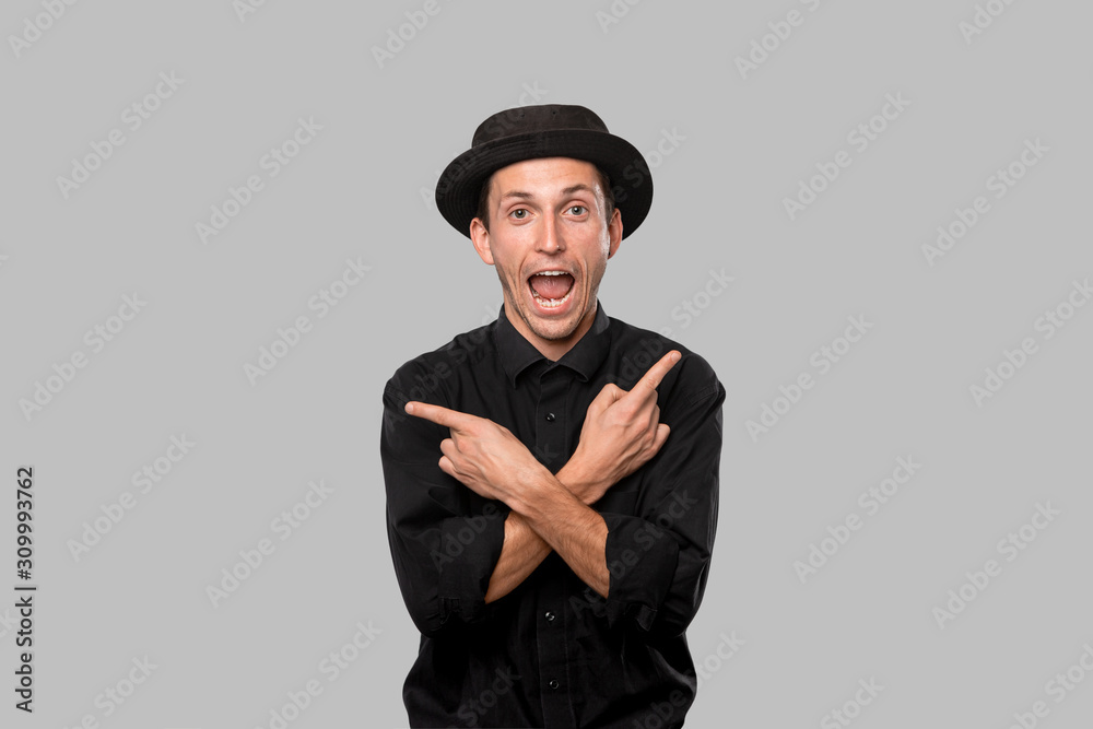 Stylish handsome man a black shirt and pork pie hat smiling and pointing with fingers at copy space Stylish handsome man a black shirt and pork pie hat smiling and pointing with fingers at copy space