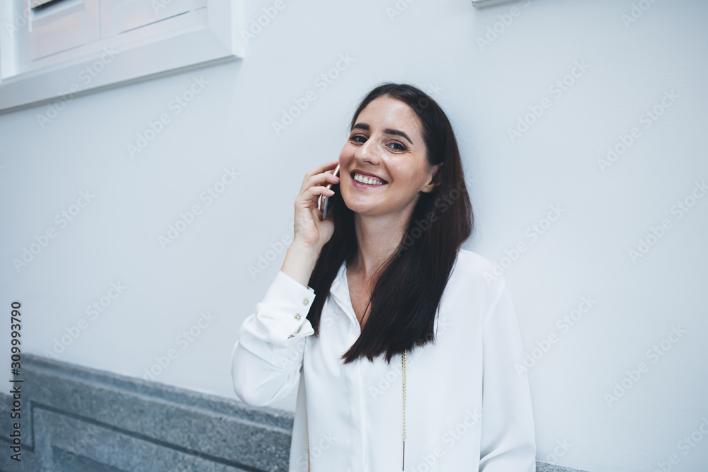 Happy lady speaking on phone leaning on wall Happy lady speaking on phone leaning on wall