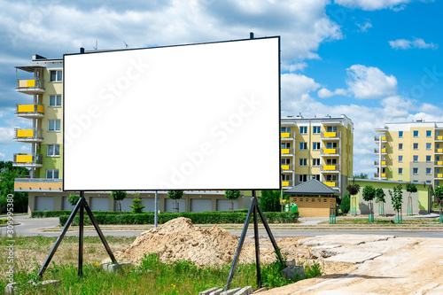 Blank white billboard for advertisement in the front of construction site against the residential buildings. photo