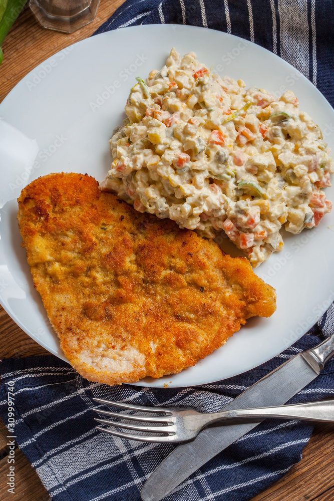 Fried pork chop in breadcrumbs, served with vegetable salad. Fried pork chop in breadcrumbs, served with vegetable salad.