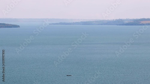 Lone fishing boat moves on open water at Lake Victoria, islands by horizon photo