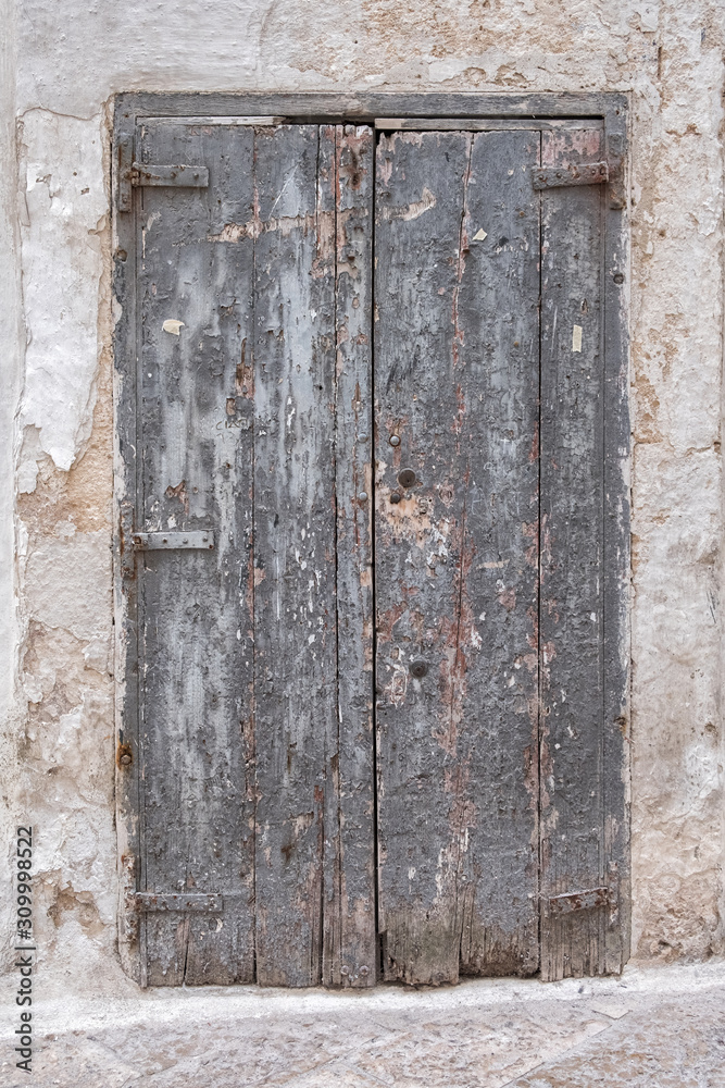 Gray wooden door in a stone wall. Closed, lock. Old rotten boards.