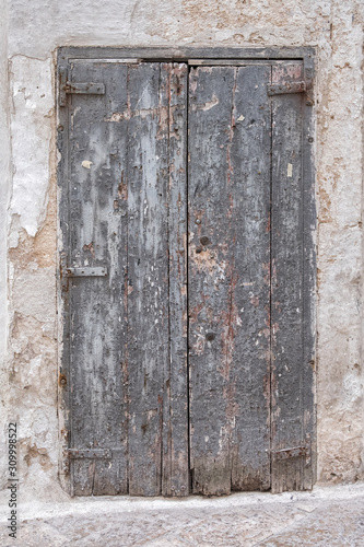 Gray wooden door in a stone wall. Closed, lock. Old rotten boards. © Arkd