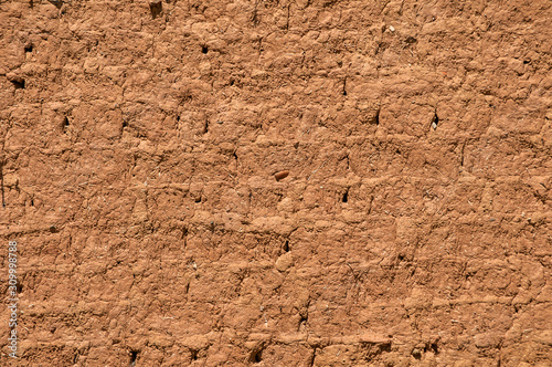 Adobe clay weathered wall of rural vintage country house closeup as clay background